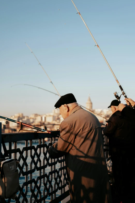 a man holding onto two fishing rods looking over a bridge