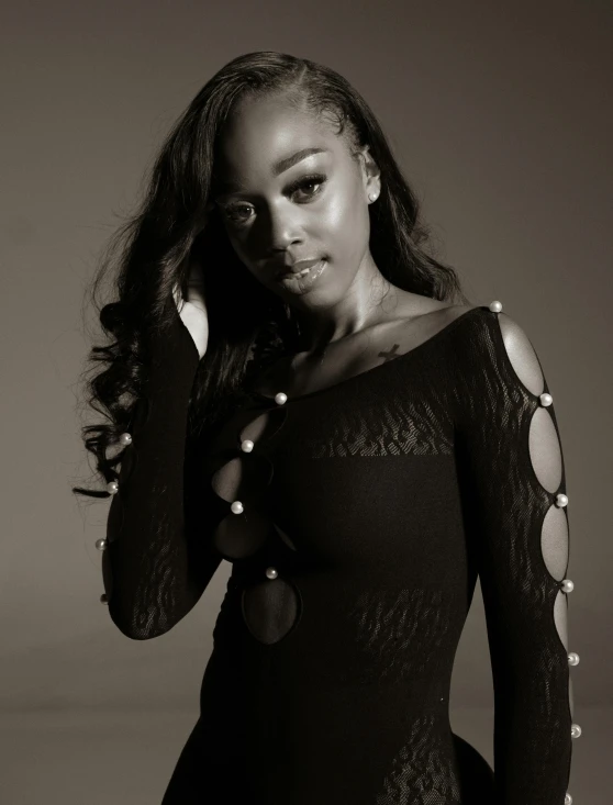 woman in a black dress with jewelry on her neck and one hand to her ear