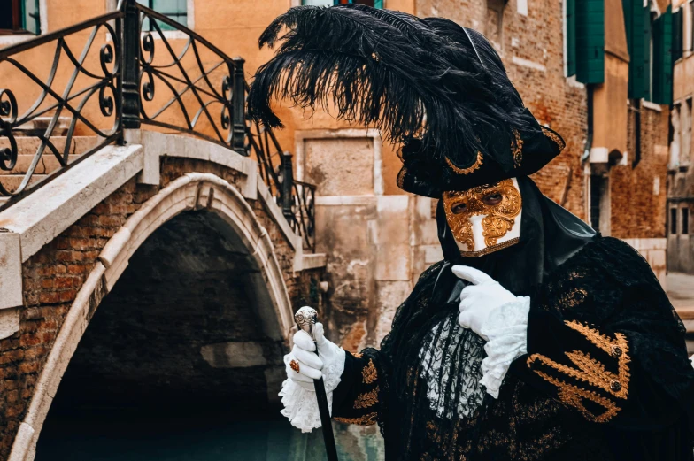 a masked man walking down a canal next to an open bridge