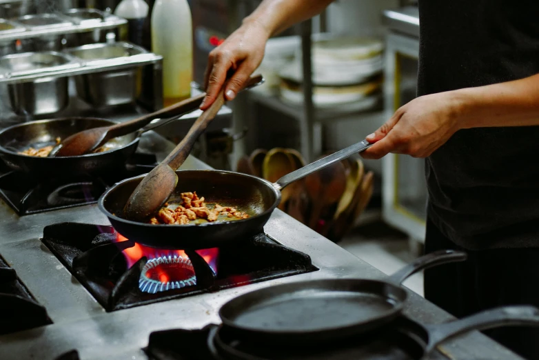 two people cooking food over the top of an oven