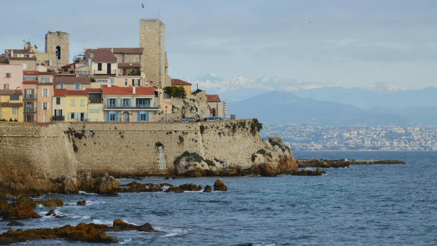 several buildings on the edge of the ocean next to a hillside