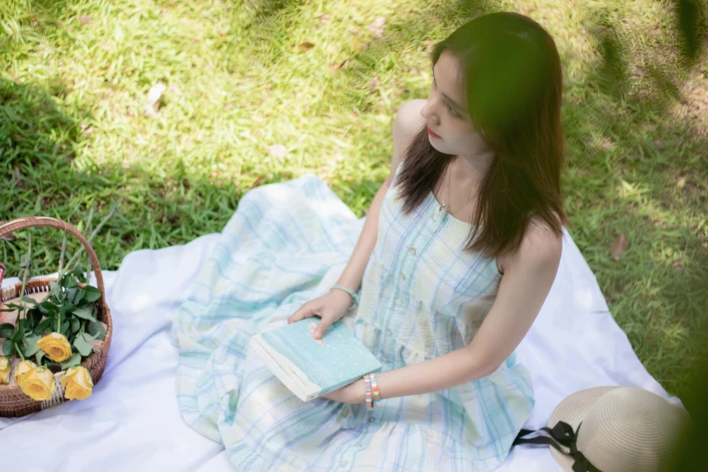 a girl wearing a striped dress sitting on the ground holding her book and purse