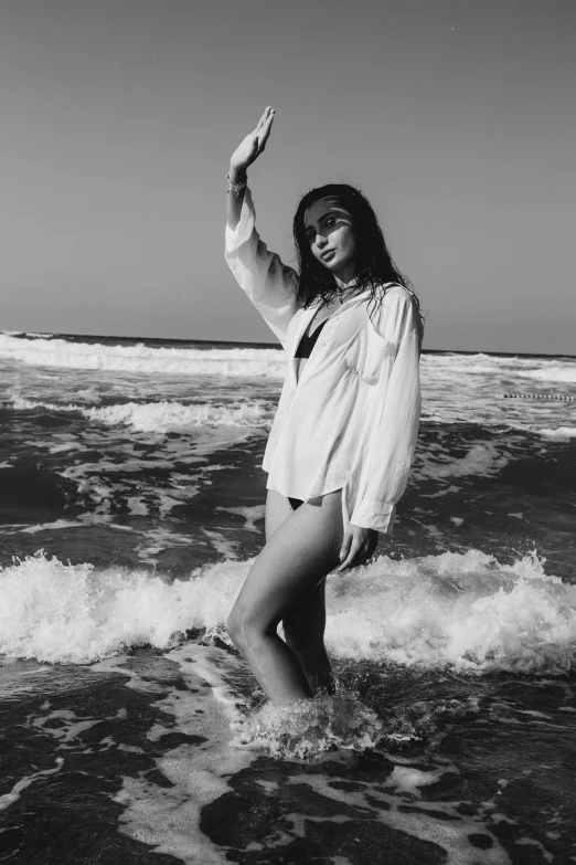 black and white pograph of a woman in a short suit walking in the ocean