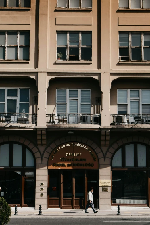 a man walks by a el sign in front of a large building