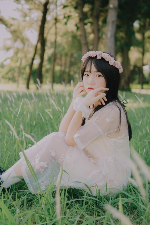 a beautiful woman sitting in the grass talking on a cell phone