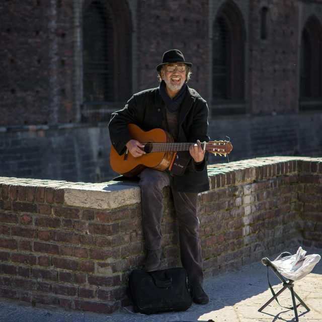 a man is holding a guitar by the wall