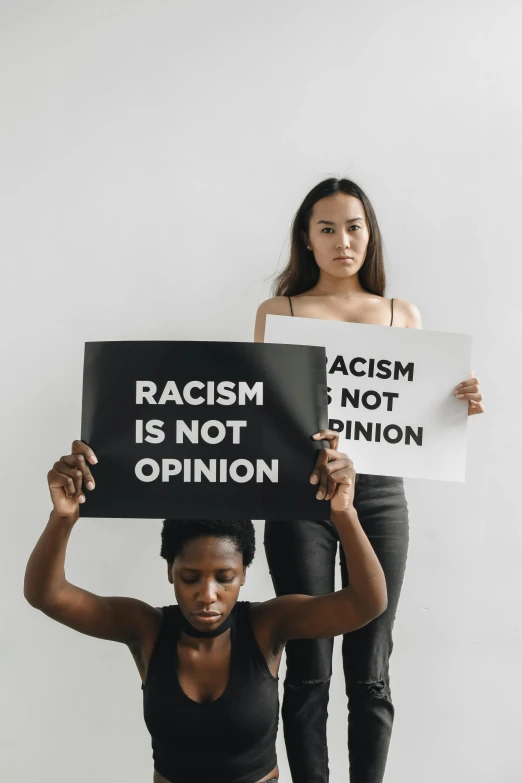 two women holding signs against racism