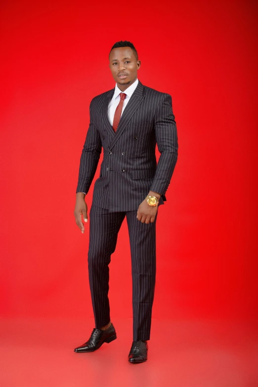 a man wearing a black and red suit stands against a red background
