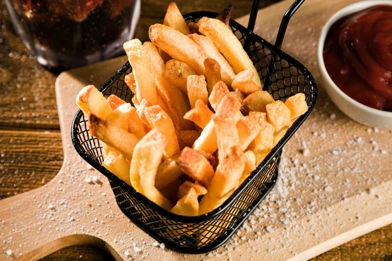 a small basket full of french fries and a glass with ketchup