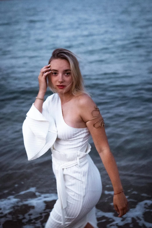 a woman in a white dress standing in front of water