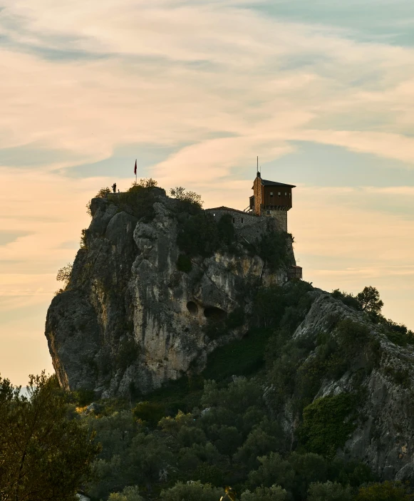 a rocky mountain with trees on top with a view of two towers