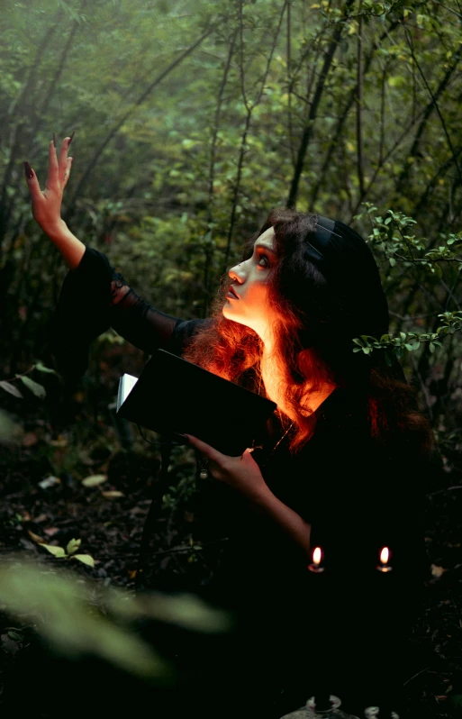 woman with glowing arm holding open book in woods