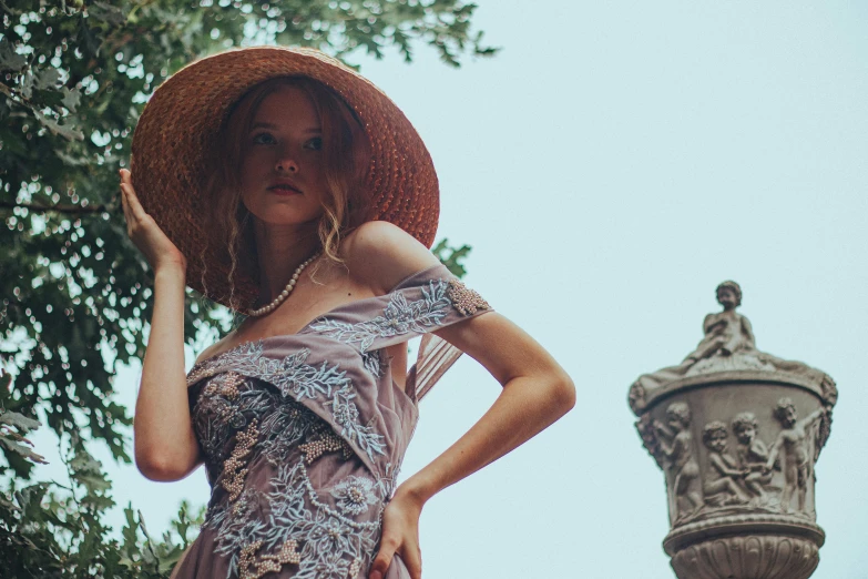 a girl wearing a large floppy hat in front of a building