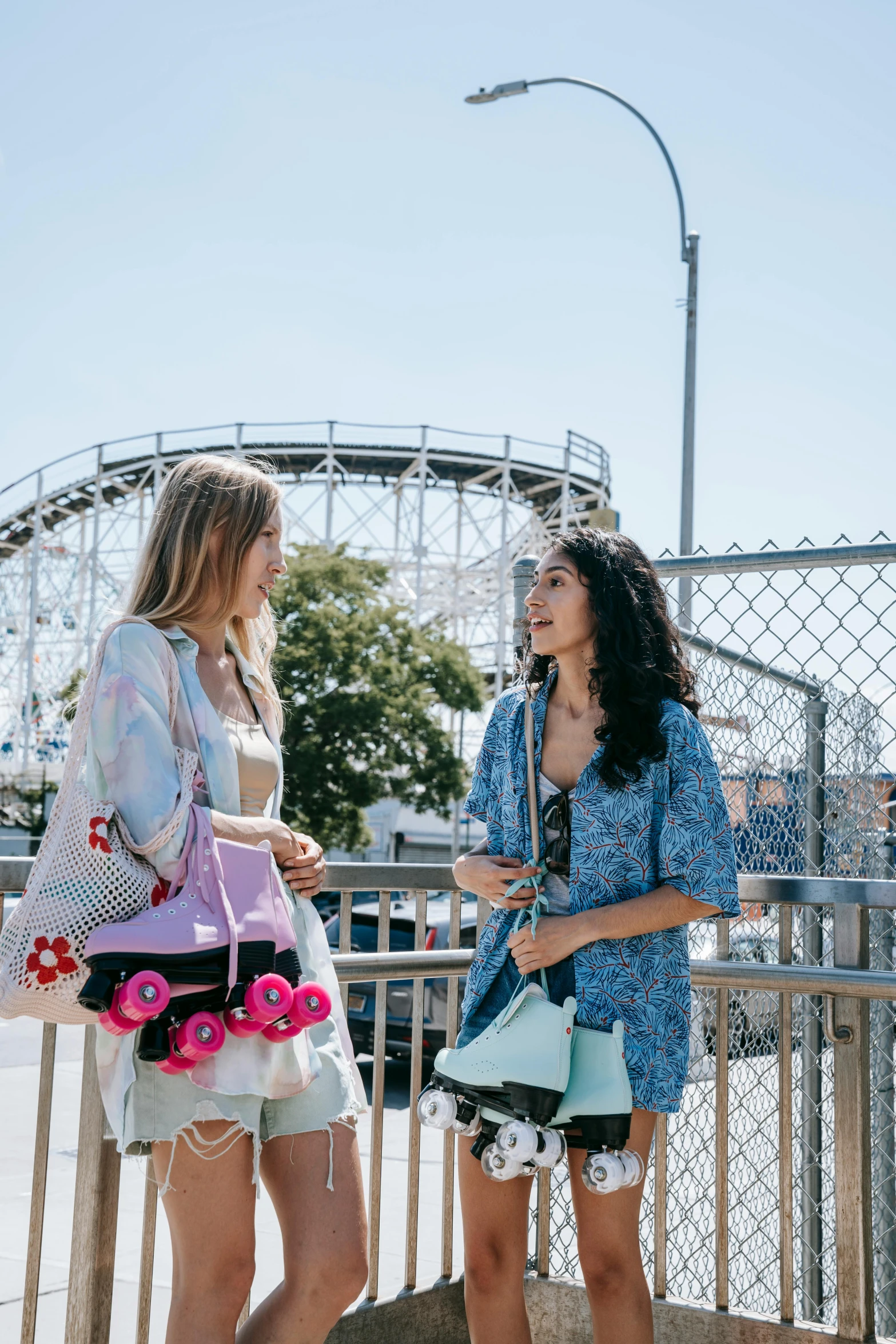 two women laugh as they walk near a roller coaster