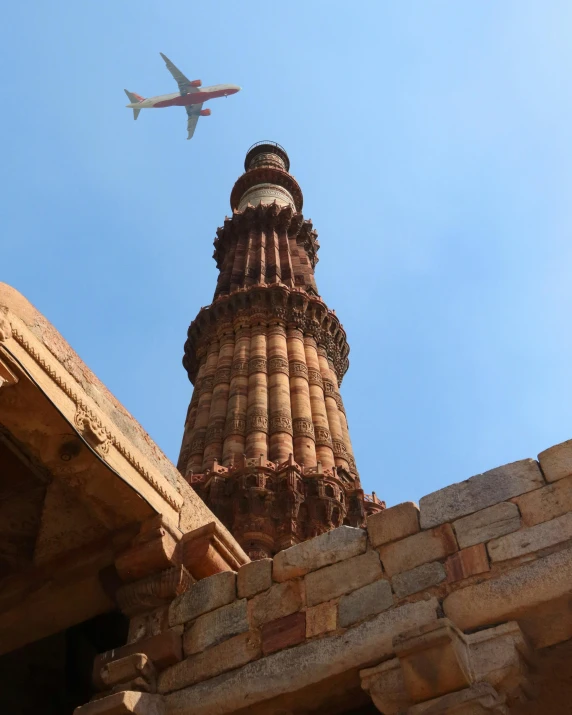 an airplane flying over a brick tower with a clock on it