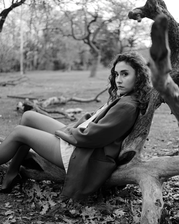 black and white pograph of a woman sitting on tree stump