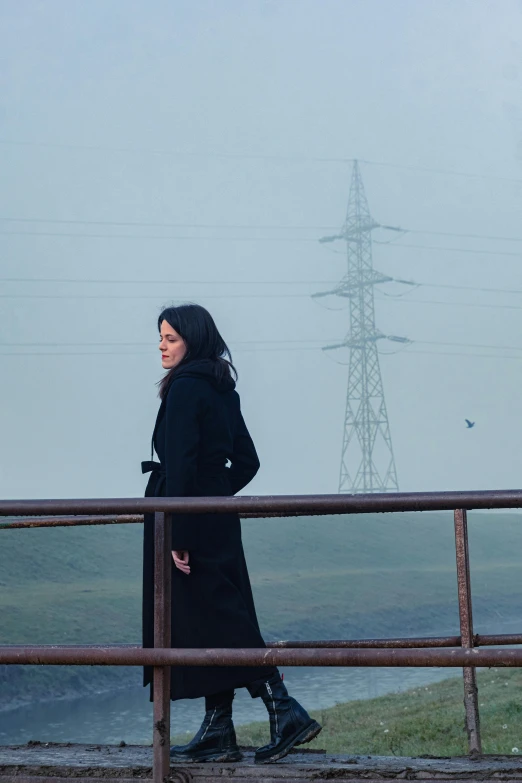 a woman standing in front of a fence next to a field