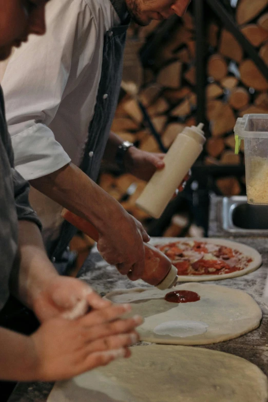 chefs are making homemade pizzas on an industrial counter