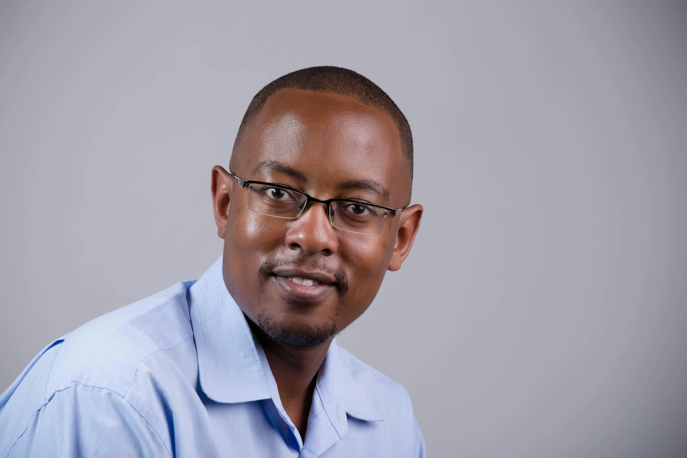 a man wearing glasses in a blue shirt and dress pants