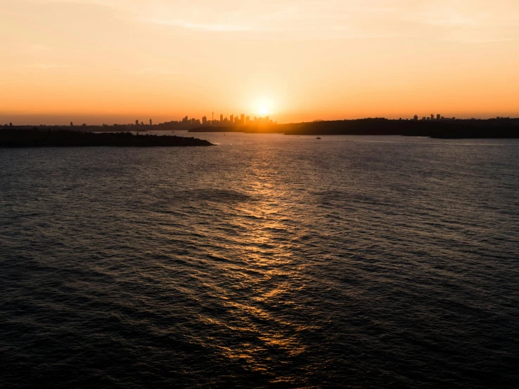 the sun setting in the horizon above a body of water