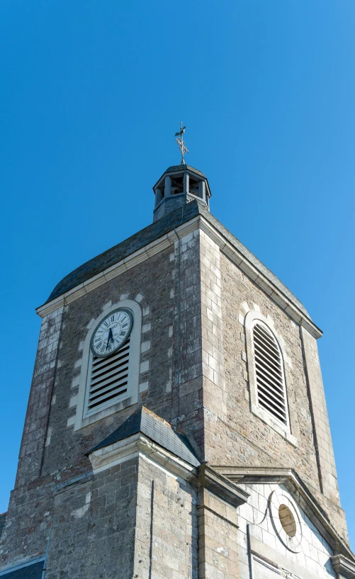 a stone clock tower with a cross on top