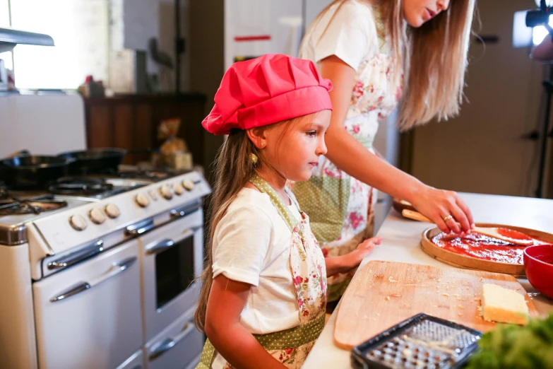 two women working in a kitchen with one of the s using a pie crust