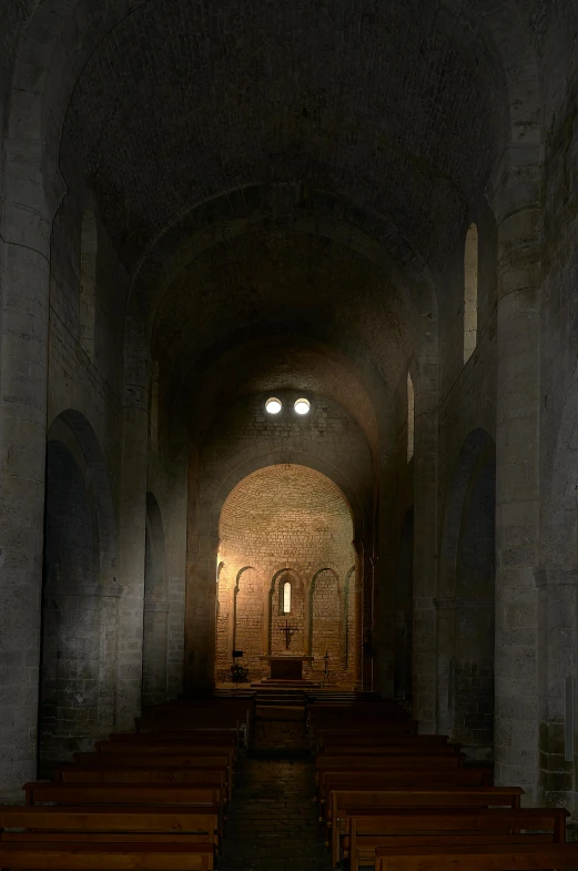 long hallway of ancient stone building with rows of wooden chairs