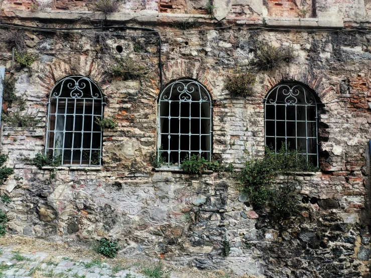 three windows with stone and iron frames on a building