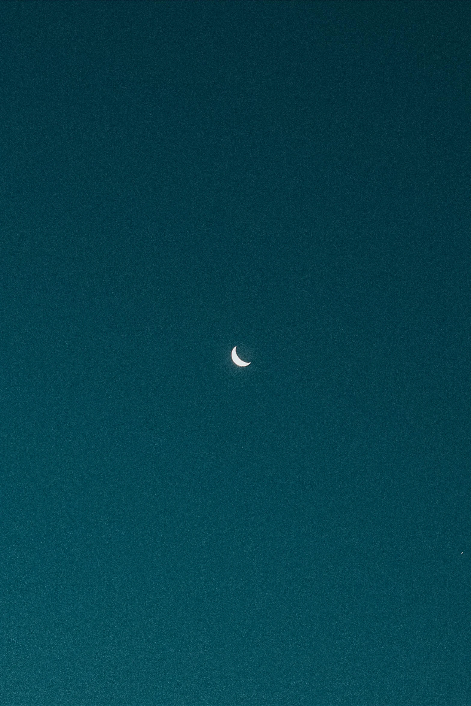 an airplane flying in the sky with a half moon visible