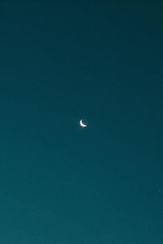 an airplane flying in the sky with a half moon visible