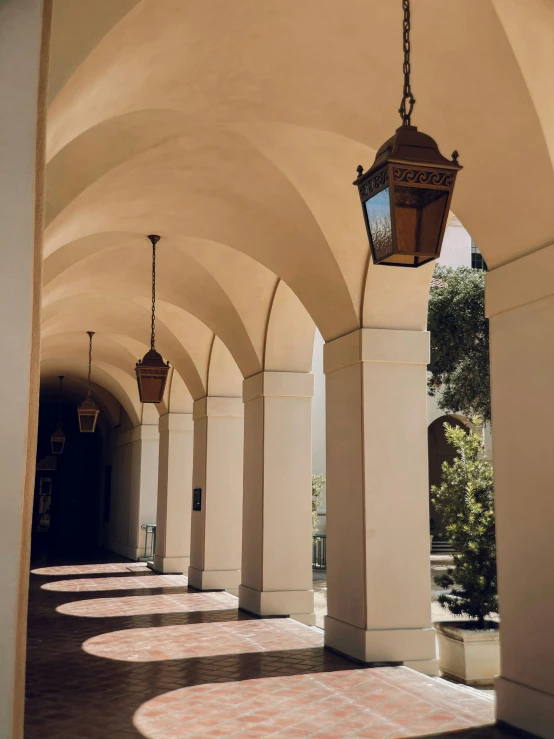 several lanterns suspended from large arches on the outside of a building