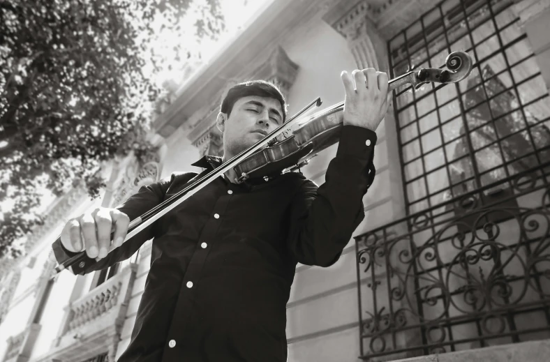 man in black jacket holding a musical instrument in front of large windows