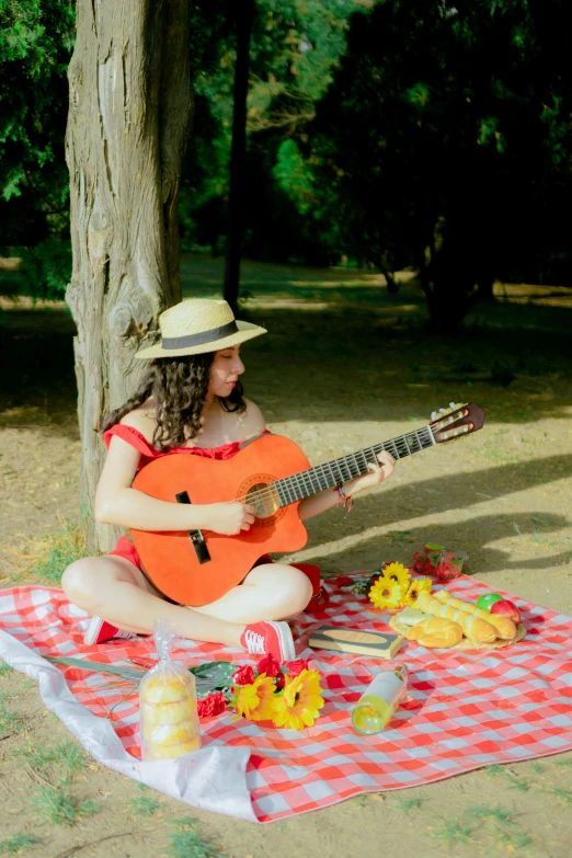 a woman sits on a picnic table with an acoustic guitar