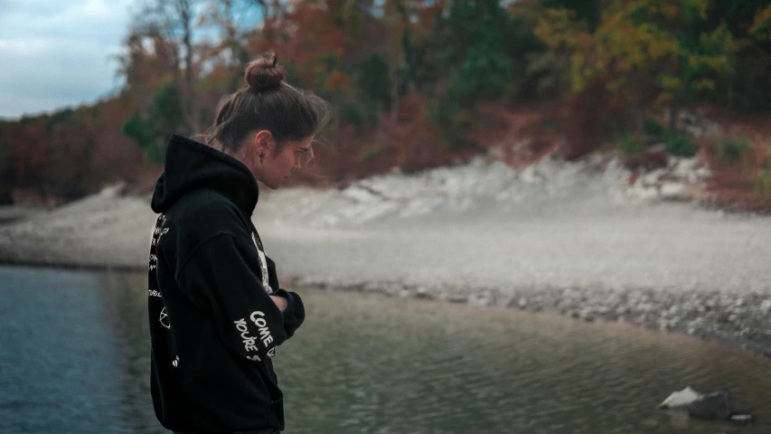 a person in black coat and hat looking at the water