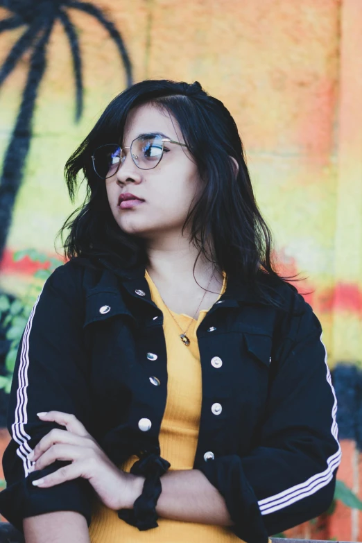 a woman with a jacket and glasses sits on a bench