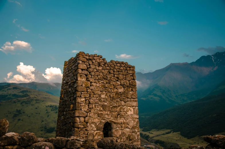 the stone tower is standing in the middle of a mountain range