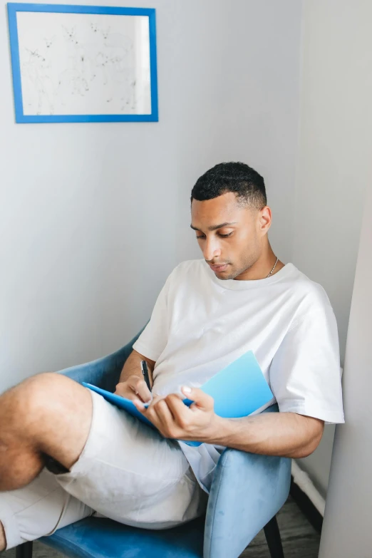 a man in white shirt and blue pants sitting on a chair