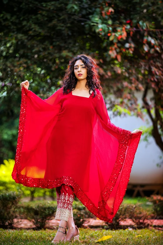 a woman with long red clothing in front of trees