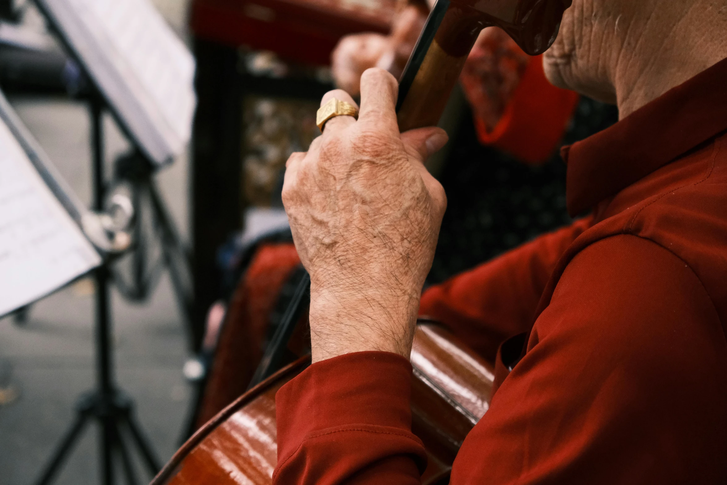 an older man in red jacket playing music on a cellphone