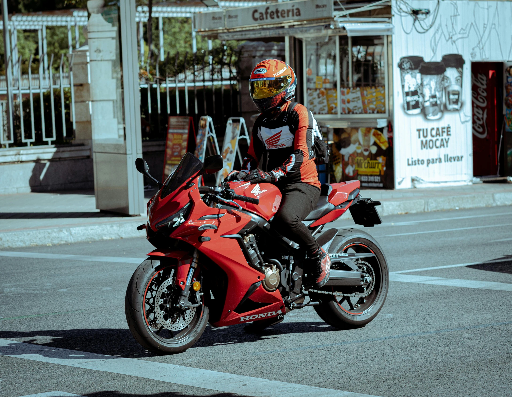 a motorcycle rider waits at the edge of a crosswalk