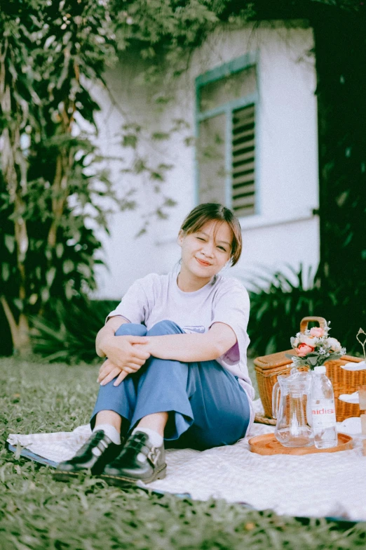 a girl is sitting down with her hands folded over her knee and she is holding an orange juice carton next to the picnic table