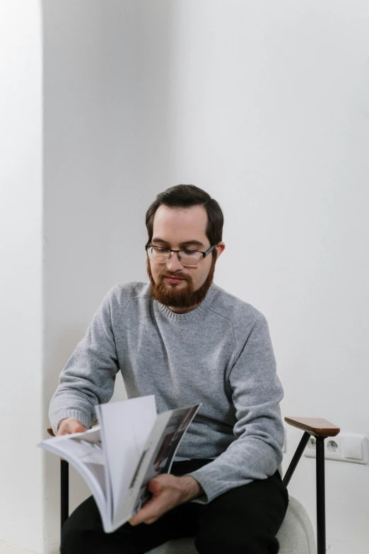 man reading a book while sitting on a chair