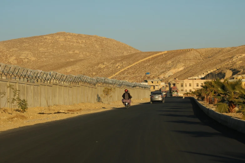 a street in the desert with a car, motorcycle and motorcycle trailer