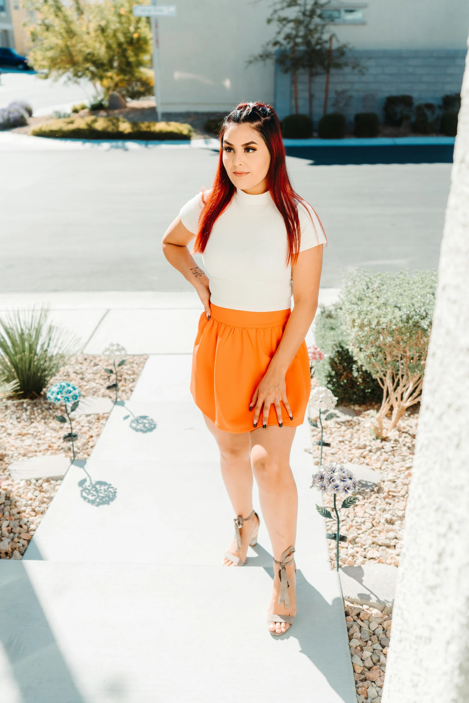 a woman standing on the sidewalk near a palm tree