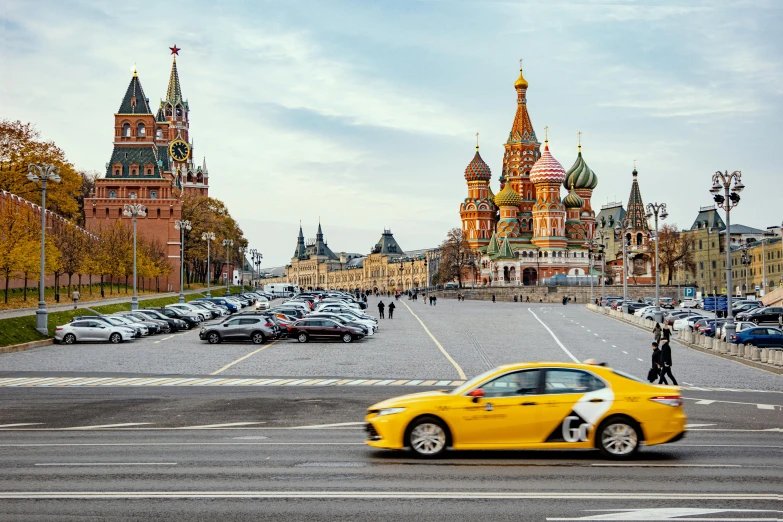 a yellow car driving down a street near tall buildings