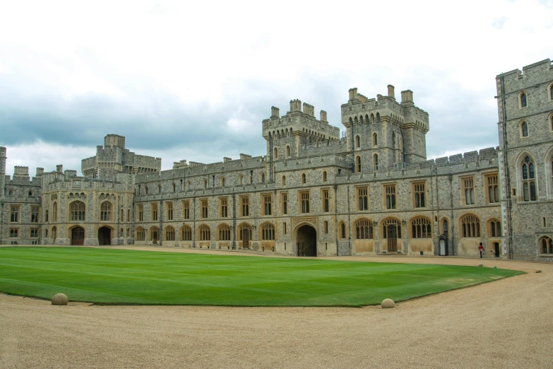 an old building with many tall towers, large windows, and green grass