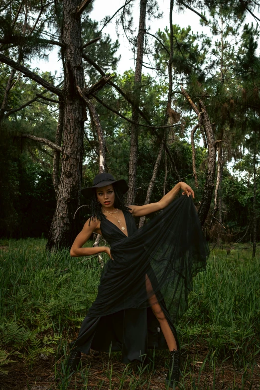 a woman poses for a pograph while surrounded by trees