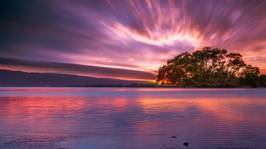 the setting sun reflects off of a calm lake