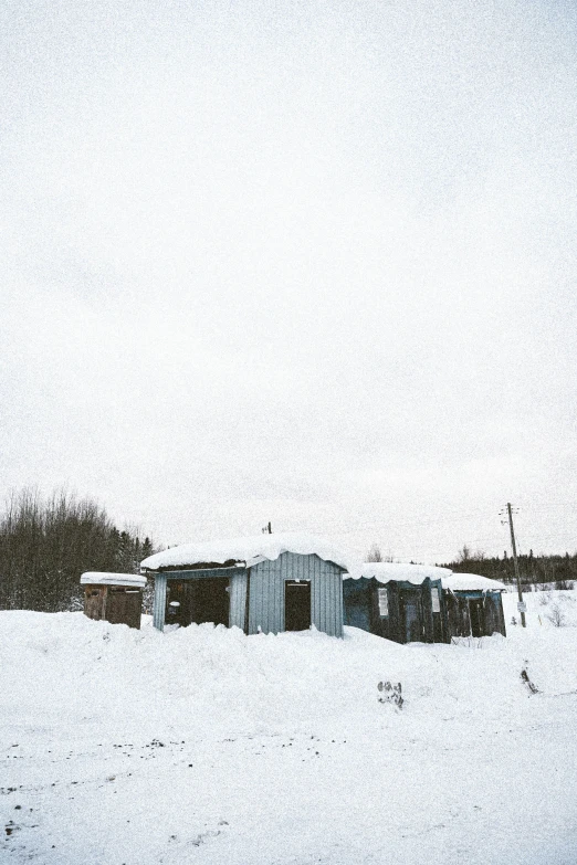 a house sits in the middle of a field covered in snow