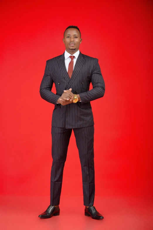 man in black suit standing on red background
